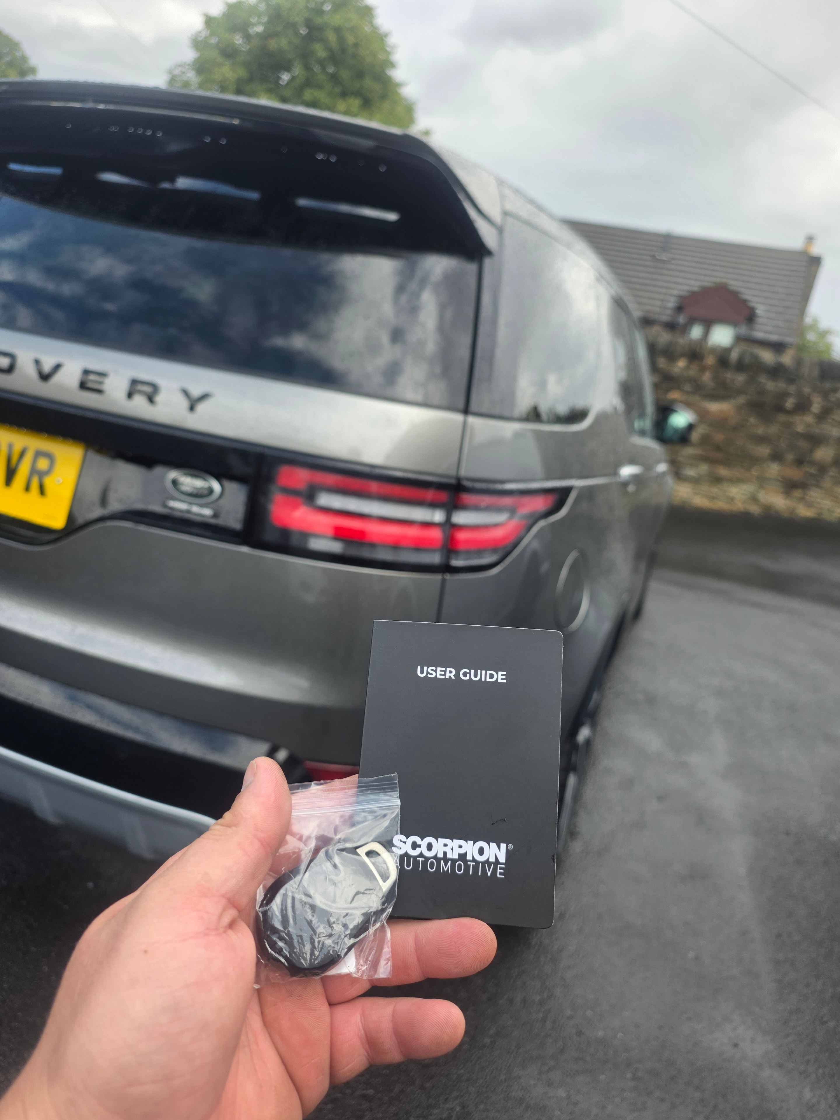 Scorpion user guide and key fob held in front of Land Rover Discovery — Meta Trak tracker installation